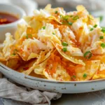 A plate of crispy Crab Rangoon Potato Chips topped with creamy crab filling, garnished with green onions and sesame seeds