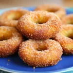 A plate of golden, Crispy Chicken and Potato Doughnuts coated in cinnamon sugar